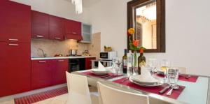 サン・ヴィート・ロ・カーポにあるCasa Jennyのキッチン(赤いキャビネット、ワイングラス付きのテーブル付)