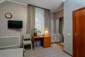 Habitación de hotel con escritorio y TV en la pared en Hotel Vizit, en Cherepovets