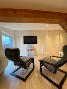 a living room with two chairs and a flat screen tv at über den Dächern von Neheim I in Arnsberg