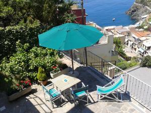 a table and chairs with an umbrella on a balcony at ARIA DI MARE, Manarola - Camere con vista mare! in Manarola