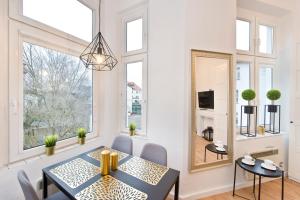 a dining room with a table and chairs and a mirror at Pomorskie Apartamenty Fiszera in Sopot