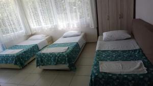 a room with two beds and a window at Samos Apart Pension in Guzelcamlı