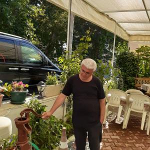 ウザーチョンガにあるSamos Apart Pensionの庭のあるパティオに男が立っている