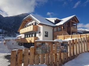 una casa nella neve con una recinzione di legno di DAVID SUITEN a Mauterndorf