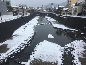 a river with snow on it in a city at hostel nedoko in Nagasaki