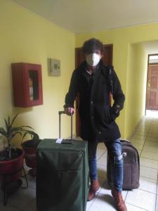 a person wearing a mask standing with a suitcase at Hospedaje de Lidia in Lima