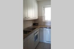 a kitchen with white cabinets and a sink and a window at Salute 106 in Leukerbad