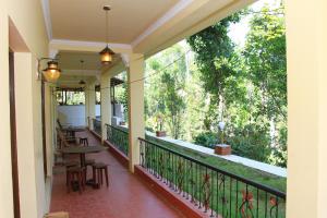 un balcón de una casa con mesa y sillas en KINGMAKER'S Plantation with River Stream en Madikeri