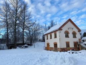 a white house with snow on the ground at Franshammars vandrarhem in Hassela