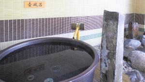 a bath tub in a bathroom with rocks at Dormy Inn Premium Kyoto Ekimae Natural Hot Spring in Kyoto