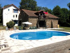 a swimming pool in front of a house at Moulin des Forges Gites, Camping et Glamping in Moutier-Malcard
