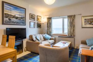 a living room with a couch and a tv at Beach Front Flat, Brodick in Brodick