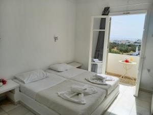 een witte slaapkamer met een bed met handdoeken erop bij Hotel Anezina in Drios
