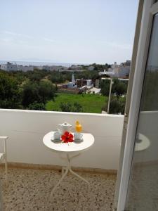 einen Tisch mit zwei Tassen und eine rote Blume auf dem Balkon in der Unterkunft Hotel Anezina in Drios