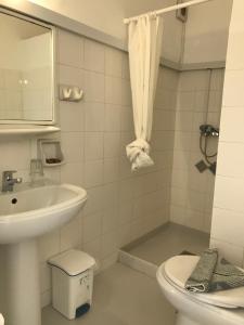 a white bathroom with a sink and a toilet at Hotel Anezina in Drios