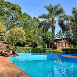 una gran piscina azul en un patio con una casa en Hotel Las Azaleas en Jardín América