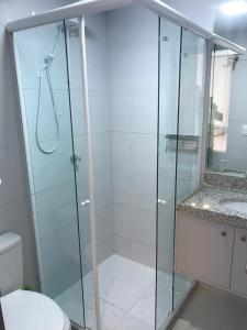 a bathroom with a glass shower with a sink at VUARNET FLATS in João Pessoa