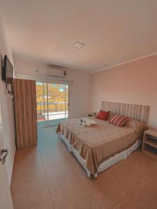 a bedroom with a bed and a large window at Buenos Vientos Complejo - Termas Chajarí in Chajarí