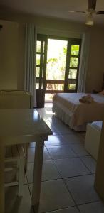 1 dormitorio con cama, mesa y ventana en Pousada Guaruja, en Bombinhas