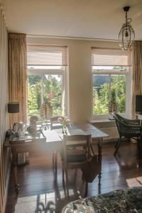 a dining room with a table and two windows at Broeks' Bed En Brood in Meerkerk