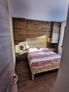 sypialnia z łóżkiem z drewnianą ścianą w obiekcie La Stua Livigno w Livigno