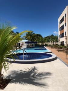 einem Pool mit einer Palme vor einem Gebäude in der Unterkunft Flat em Guarajuba in Guarajuba