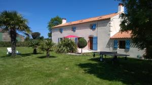una casa bianca con un tavolo da picnic nel cortile di Corps de ferme spacieux avec grand jardin, 10 personnes a LʼAiguillon-sur-Vie