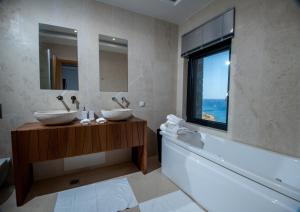 a bathroom with two sinks and a tub and a window at Villa Gina by Elounda Island View Villas in Agios Nikolaos