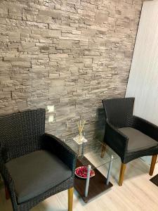 two chairs and a table in front of a brick wall at Apartament Catalin 1 in Arad