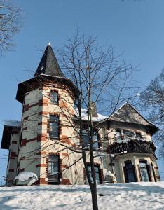 ein großes Gebäude mit einem Turm im Schnee in der Unterkunft Turmvilla Vogtland in Oelsnitz