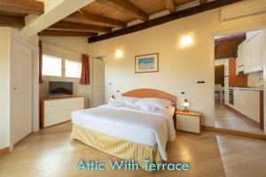 a bedroom with a large white bed and a kitchen at Santo Stefano Apartments - BolognaRooms in Bologna