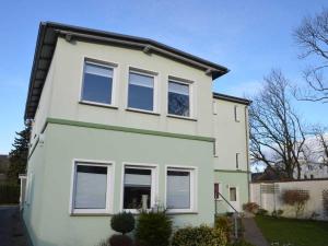 a white house with windows on a street at Ferienwohnung Anne mit Sonnenterra in Altefähr