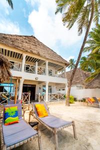 a beach with chairs, tables, and umbrellas at The African Paradise Beach Hotel in Bwejuu