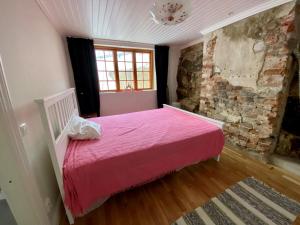 a bedroom with a pink bed and a brick wall at Franshammars vandrarhem in Hassela