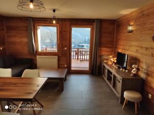 a living room with a table and a tv and a couch at LA BRESSE - Appartement de Charme in La Bresse