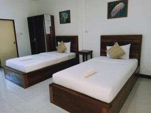 2 Betten in einem Hotelzimmer mit weißen Wänden in der Unterkunft Rachawadee House in Phangnga