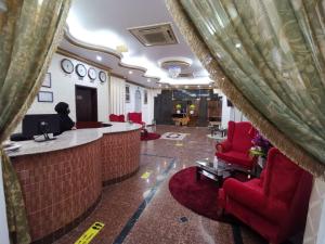 um átrio do hotel com cadeiras vermelhas e um bar em سماء البريمى للشقق الفندقية em Ţawī ‘Aqdah
