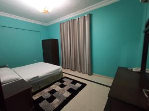 a bedroom with blue walls and a bed with a rug at سماء البريمى للشقق الفندقية in Ţawī ‘Aqdah +15 photos