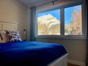 a bedroom with a blue bed and a large window at Mountain View Bed & Breakfast in Banff