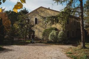 a man walking in front of a stone house at Casa Monteluro - B&b in Tavullia