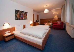 フォルバックにあるLandgasthof-Pension Ochsenのベッドルーム(大型ベッド1台、赤いソファ付)