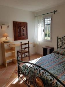 a bedroom with a bed and a desk and a window at Villa Su Trechesu in Orosei