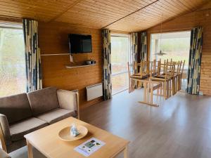 een woonkamer met een bank, stoelen en een tafel bij Hummingen Camping hus 2 in Dannemare