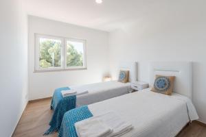 two beds in a white room with a window at Prainha Luxury Apartment in Alvor +52 photos