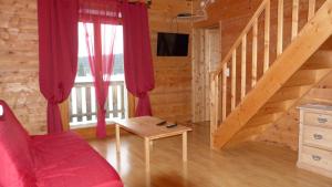a living room with a red couch and a staircase at LA GRANGE DE HAUTE-JOUX in Les Fourgs