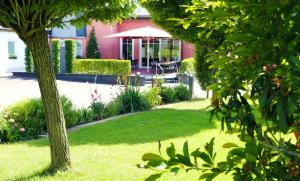 Mettendorf的住宿－Hotel Kickert，花园设有粉红色的房子,配有桌子和遮阳伞
