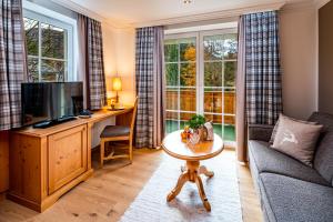 sala de estar con sofá, TV y mesa en Hotel Fischerwirt Natur WaldSPA, en Faistenau