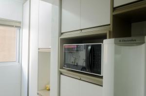 um micro-ondas na cozinha com armários brancos em No CENTRO de Cascavel, atras do Ibis, confortavel e bom gosto em Cascavel