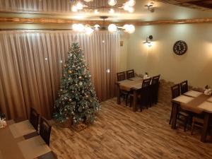 a christmas tree in a restaurant with tables and chairs at U Slavika in Yasinya