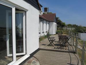 una terraza de madera con sillas y mesas en una casa en Upton Cross B&B, en Bude